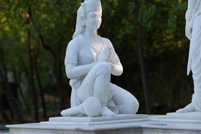 White marble figure kneeling on a plinth outdoors
