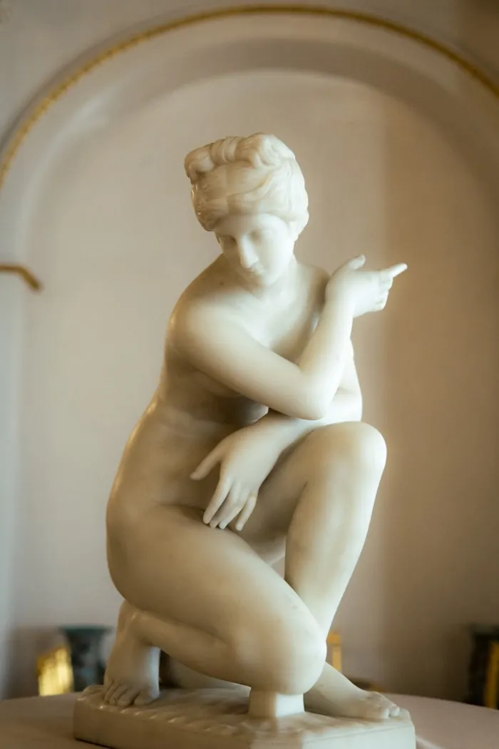 Marble sculpture of a kneeling figure in an arched alcove