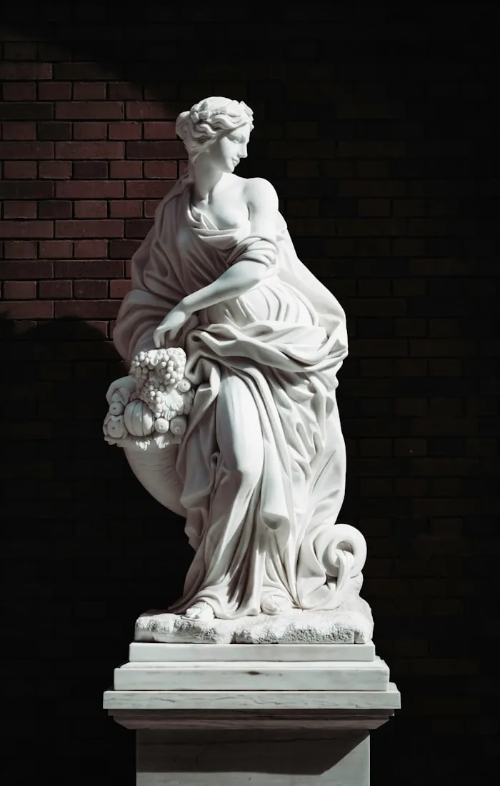 Classical marble sculpture of a draped female figure on a pedestal